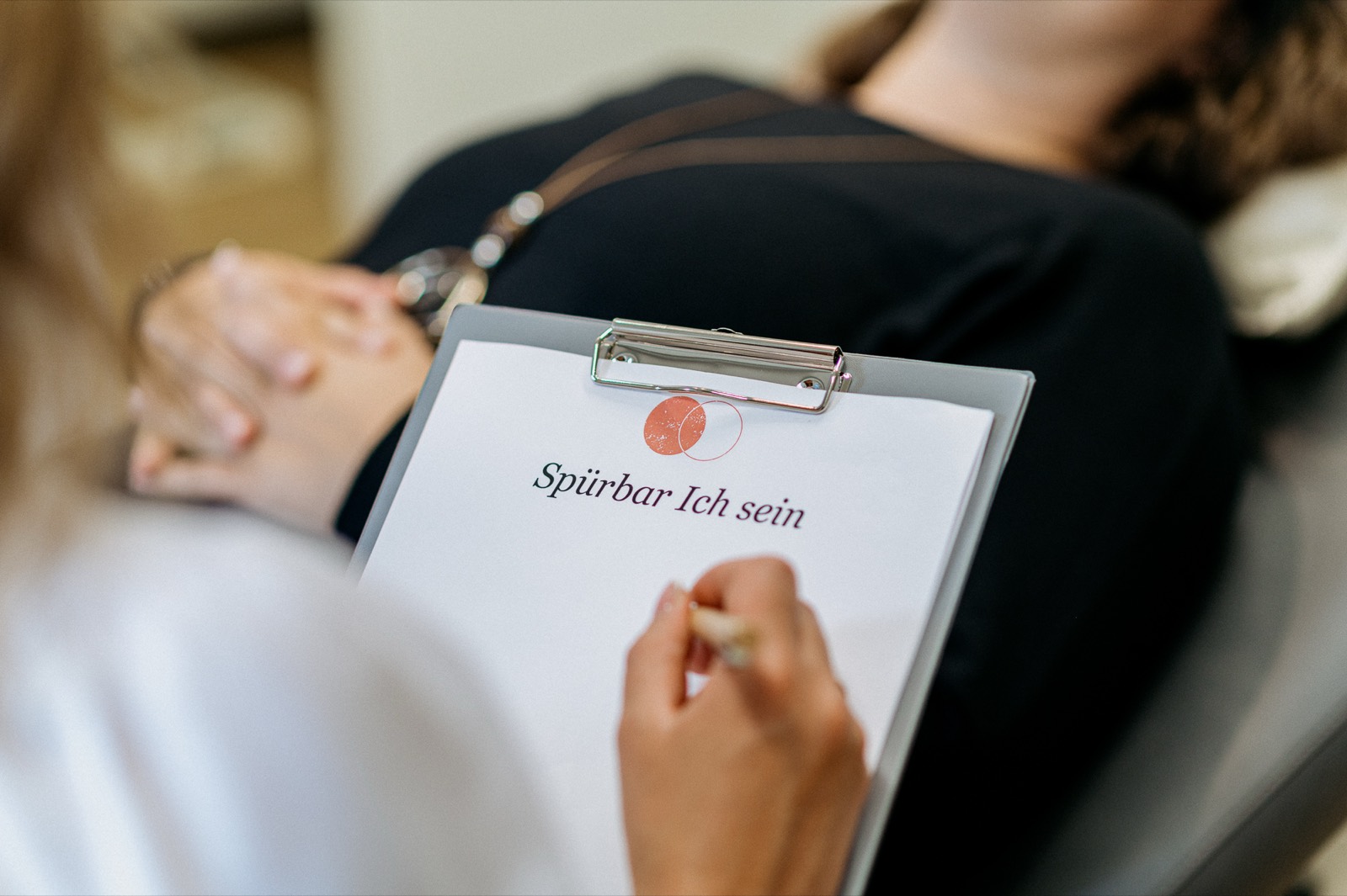 Hypnose-Sitzung in der Praxis: Stefanie Fronert macht Notizen, während eine Person entspannt liegt